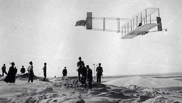 historic black and white image of a crowd watching one of the first gliders in 1911
