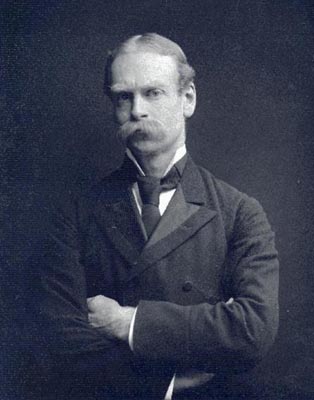 Historic image of man in suit and tie, arms crossed, with a long mustache Historic image of man in suit and tie, arms crossed, with a long mustache