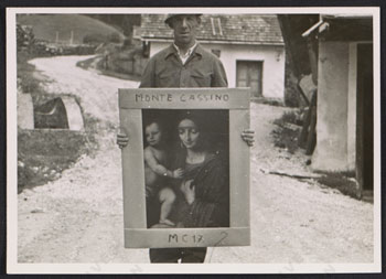 A man standing on a stone road holds a painting of the Madonna and child