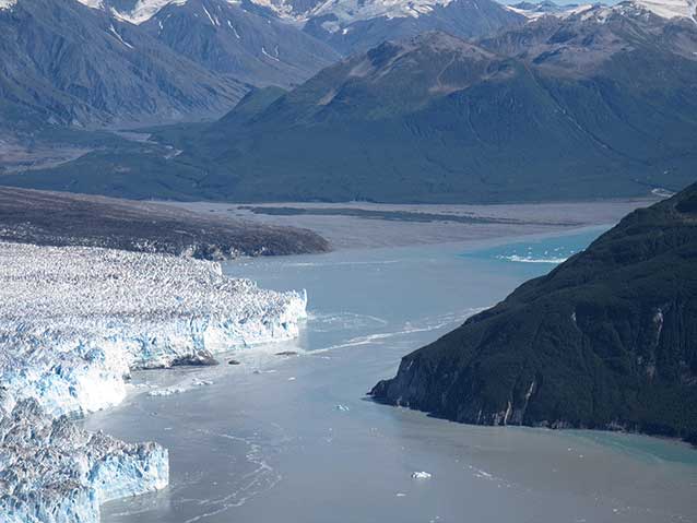 aeria view of a large tidewater glacier close to the mountainous side of a fjord