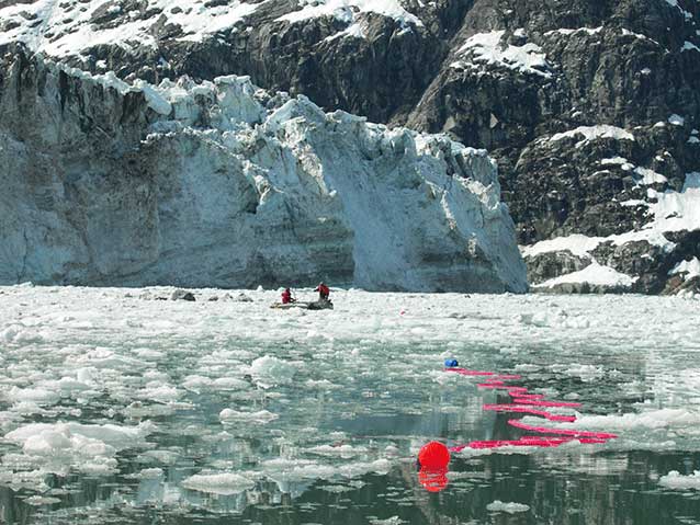 people in a boat line out a reddish net in an icy bay