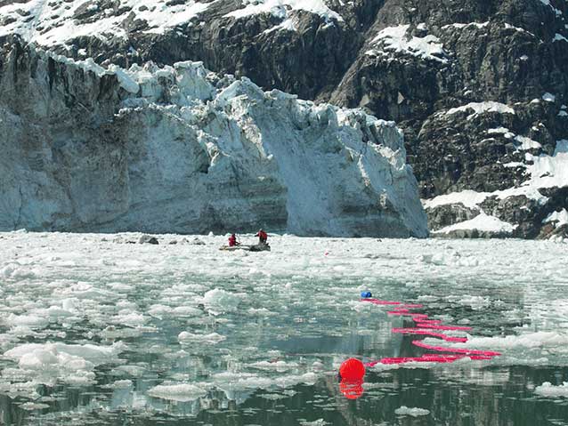 people in a boat line out a reddish net in an icy bay people in a boat line out a reddish net in an icy bay