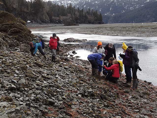 kids and teachers standing on a rocky beach