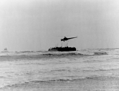 historic black and white image, helicopter in the distance over the sea