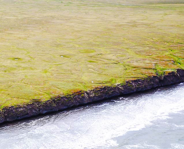 aerial view of a tree-less coastline being eroded by the ocean aerial view of a tree-less coastline being eroded by the ocean