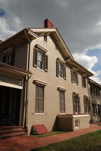 Clouds move over a two-story house with rows of windows and a brick sidewalk Clouds move over a two-story house with rows of windows and a brick sidewalk