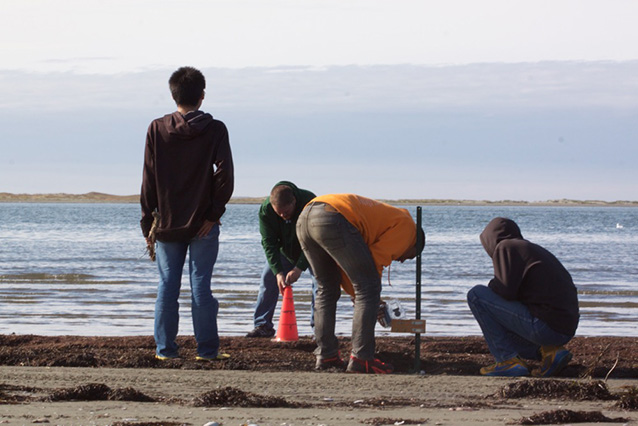 four people on a beach setting up cameras