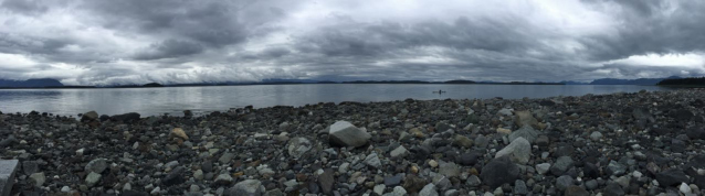 a rocky beach and calm ocean under heavy gray clouds