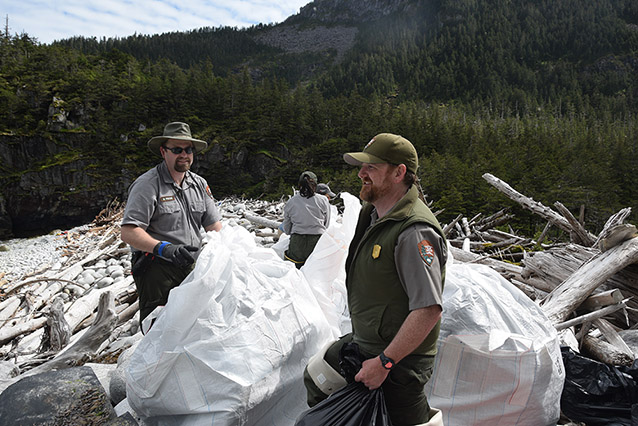 park rangers putting trash into plastic bags park rangers putting trash into plastic bags