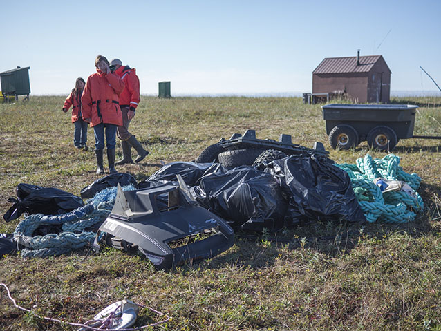 people standing near numerous bags of trash in a tree-less meadow