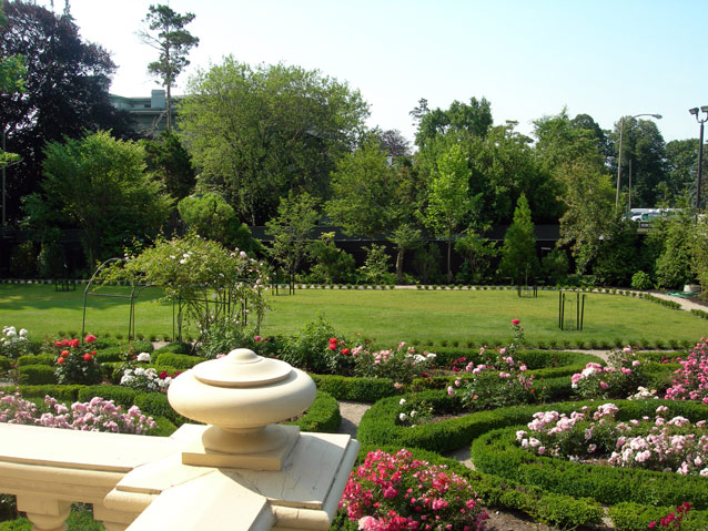 View over the edge of a railing to an ornamental garden with beds lined in boxwood View over the edge of a railing to an ornamental garden with beds lined in boxwood