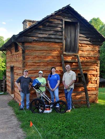 Two men and two women with survey equipment in front of a log cabin Two men and two women with survey equipment in front of a log cabin