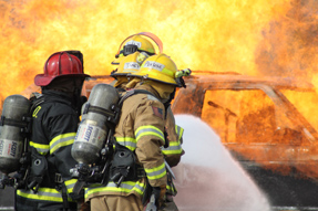 Fire crew aggressively controls a vehicle fire for a simulated rescue exercise.