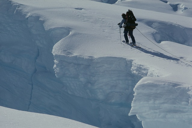 A mountaineer walks beside a deep crevasse (Denali National Park, AK) A mountaineer walks beside a deep crevasse (Denali National Park, AK)