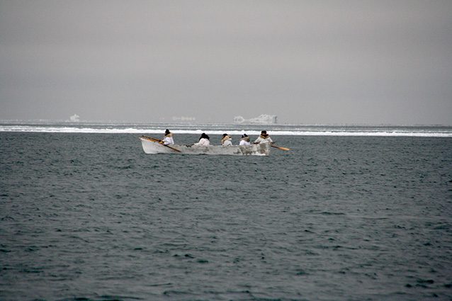 a group of men in a low boat in the ocean