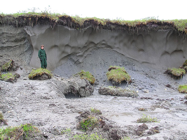 a man standing near a slump in the land that is twice as tall as him