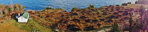 View of small structure, lake, and burned area from high vantage point.