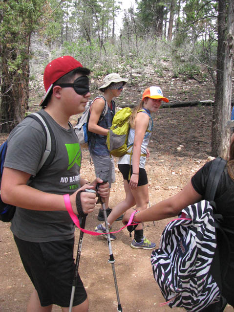 A blind folded, sighted student is led on the trail during a Leading the Way exercise.