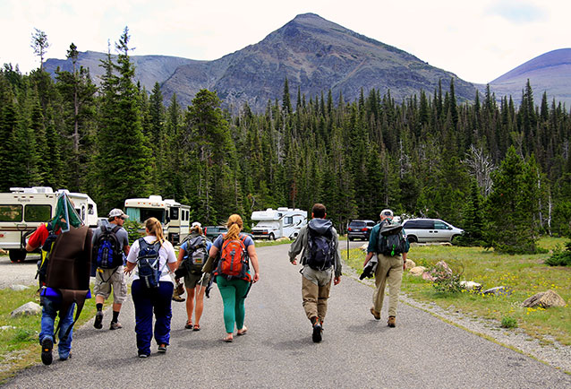 A group of students head down the road toward parked cars.