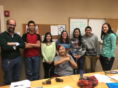 a group of youth stand being an elder holding an artifact