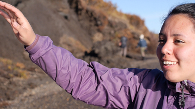 a student raises her hand while on a beach