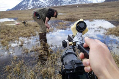 a person walks through a swamp while another person films