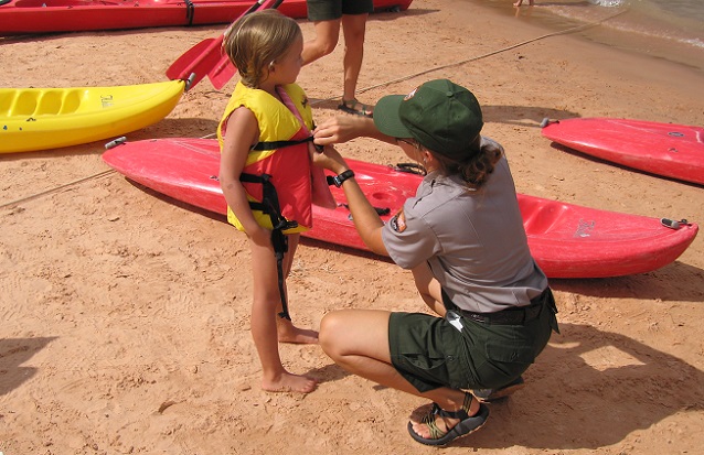 NPS Ranger helping a young child put on a properly fitted U.S. Coast Guard approved life jacket NPS Ranger helping a young child put on a properly fitted U.S. Coast Guard approved life jacket