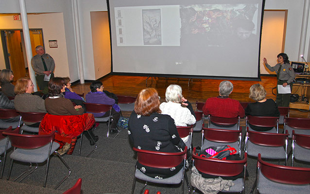 Park service employees welcome visitor to talk and live, video feed of speakers.