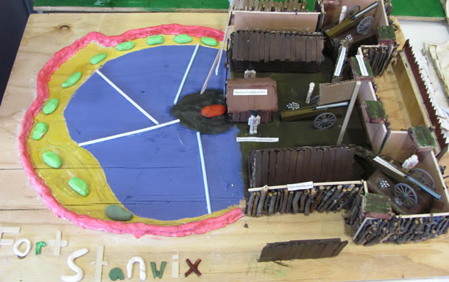 A clay and wood model. Half of it is colorful cell structures, the other half is the fort.