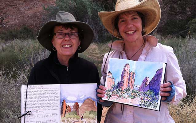 two women hold up watercolor paintings