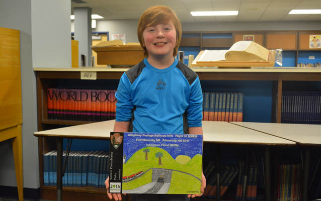 Boy with red hair and a blue shirt holding artwork