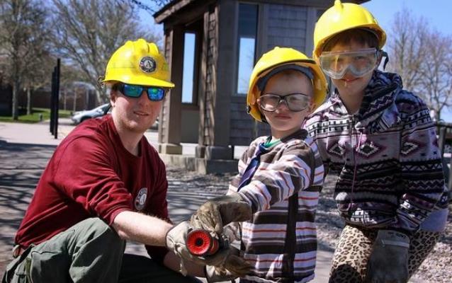 Two youngsters learn about a fire hose with a park firefighter.