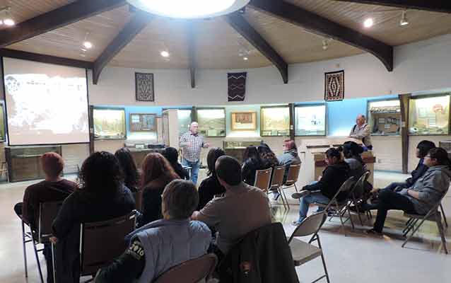 High school seniors and park rangers gather in a museum.
