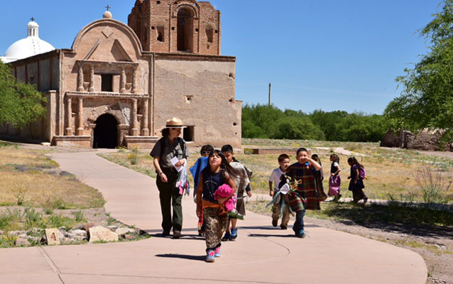 ranger and students in costumes walk on path in front of church
