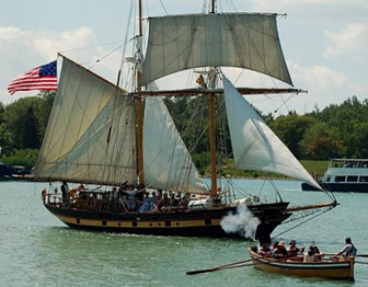 A rowboat approaches a two-masted sailing ship flying the American flag.