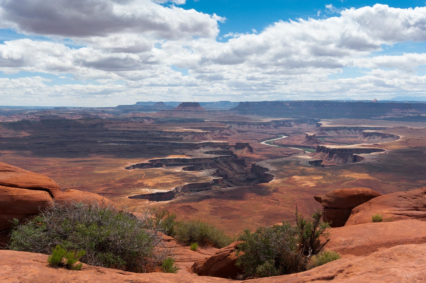 A vast view of canyons and buttes with a river winding through the center