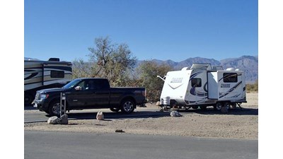 a truck and camper on a paved site with sparse vegetation