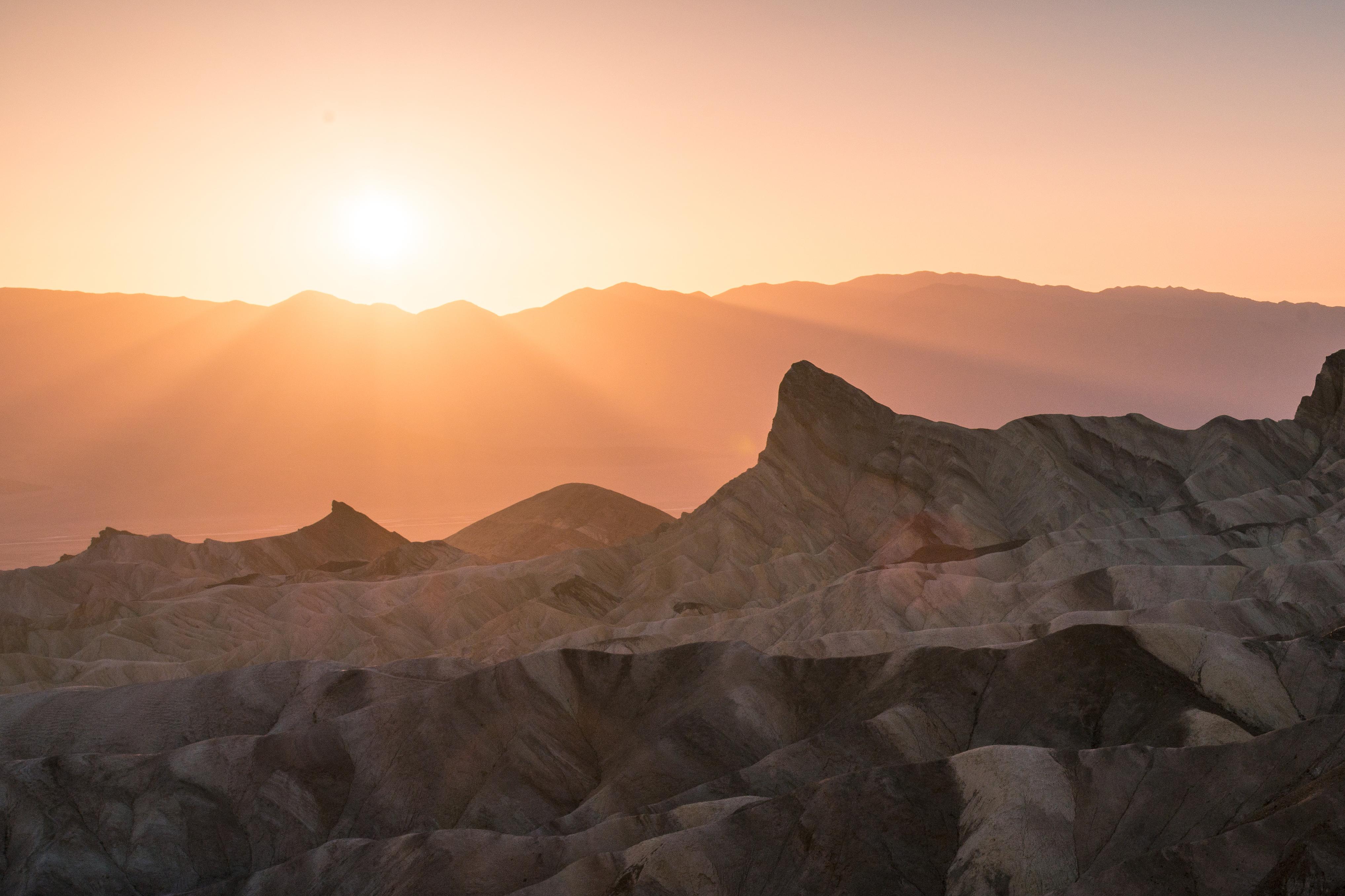 badlands bathed in pale pink and orange light from the setting sun