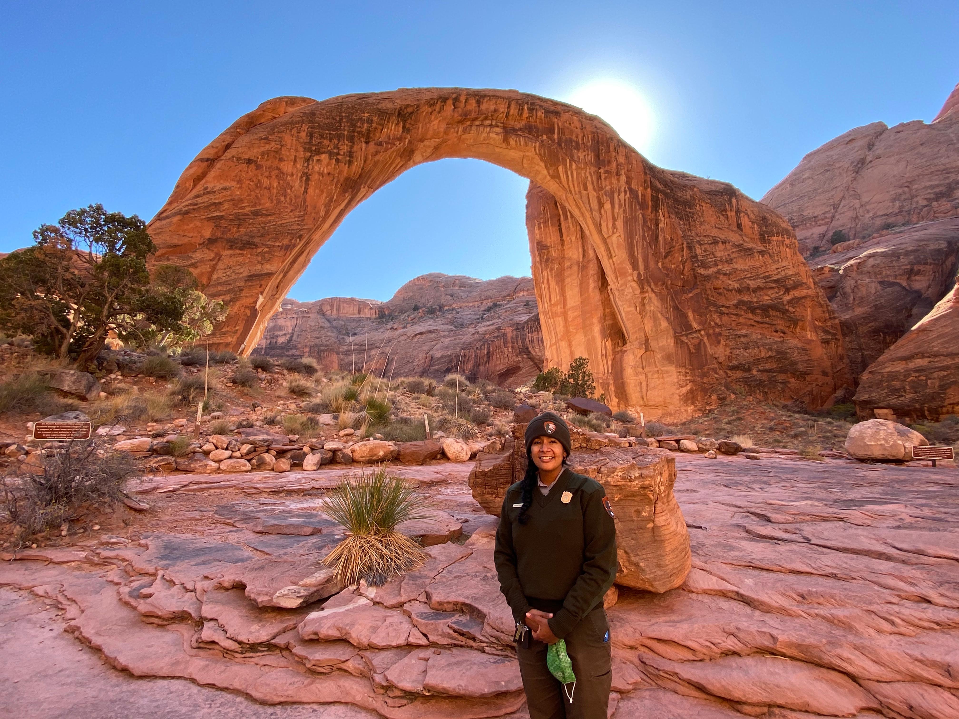 Park Ranger standing in front of perfectly curved sandstone arch