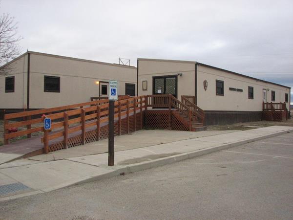 Two tan trailers with wood railed ramp leading to them.