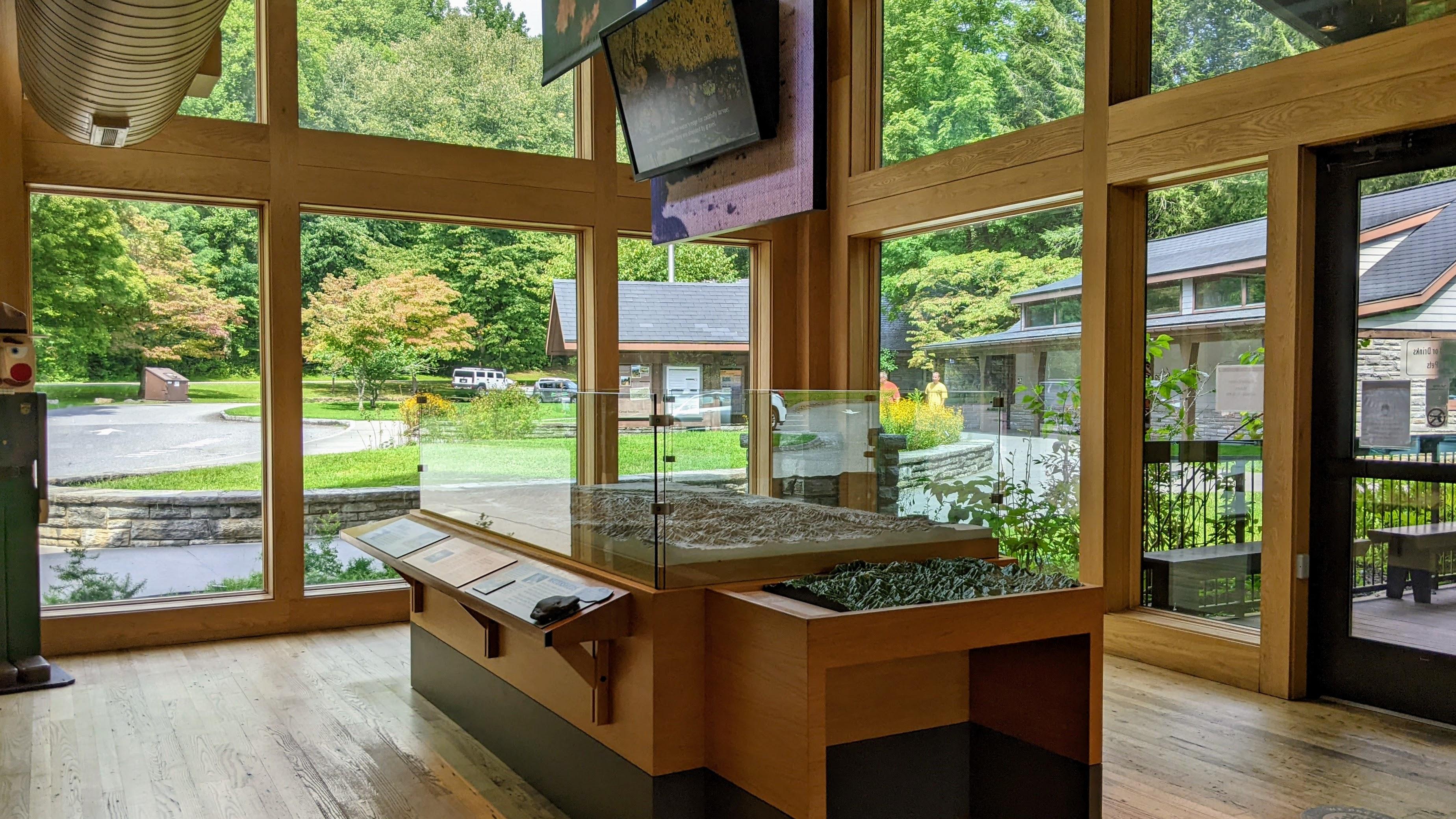 A topographic map display in a room with large windows and a TV display plus park information