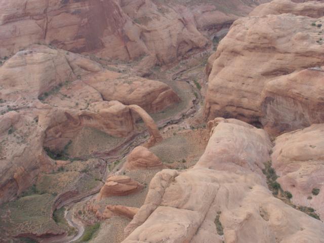 An aerial photo of a natural stone arch in a red rock canyon