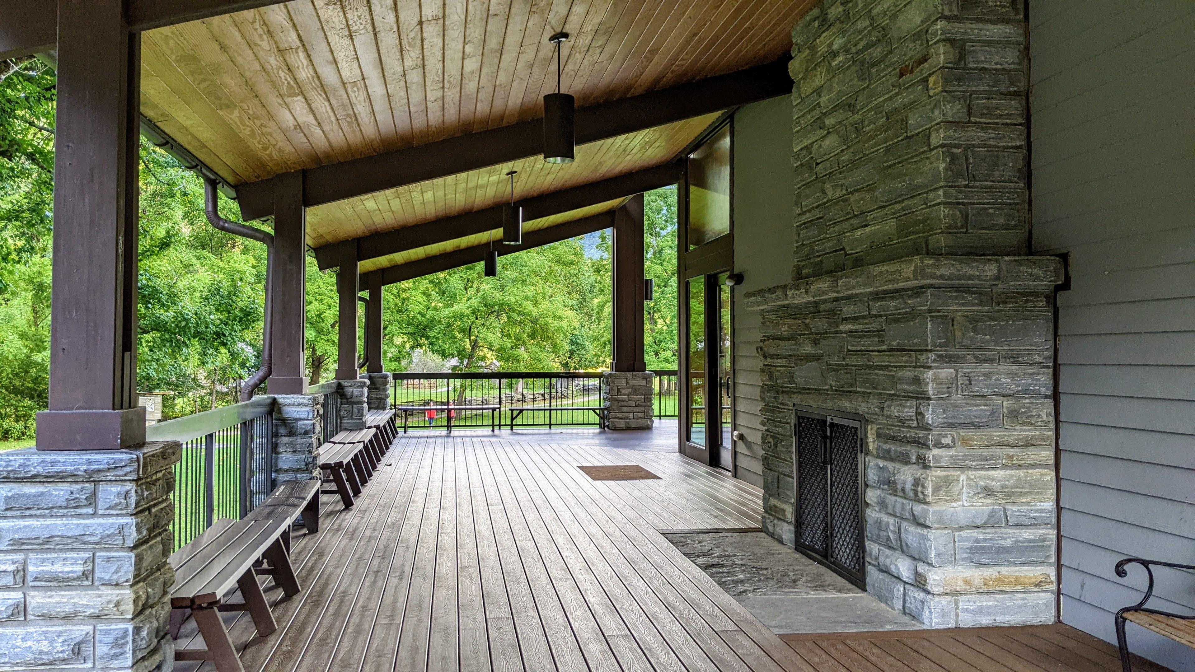 A covered porch area with a chimney, benches, and light fixtures on the ceiling.
