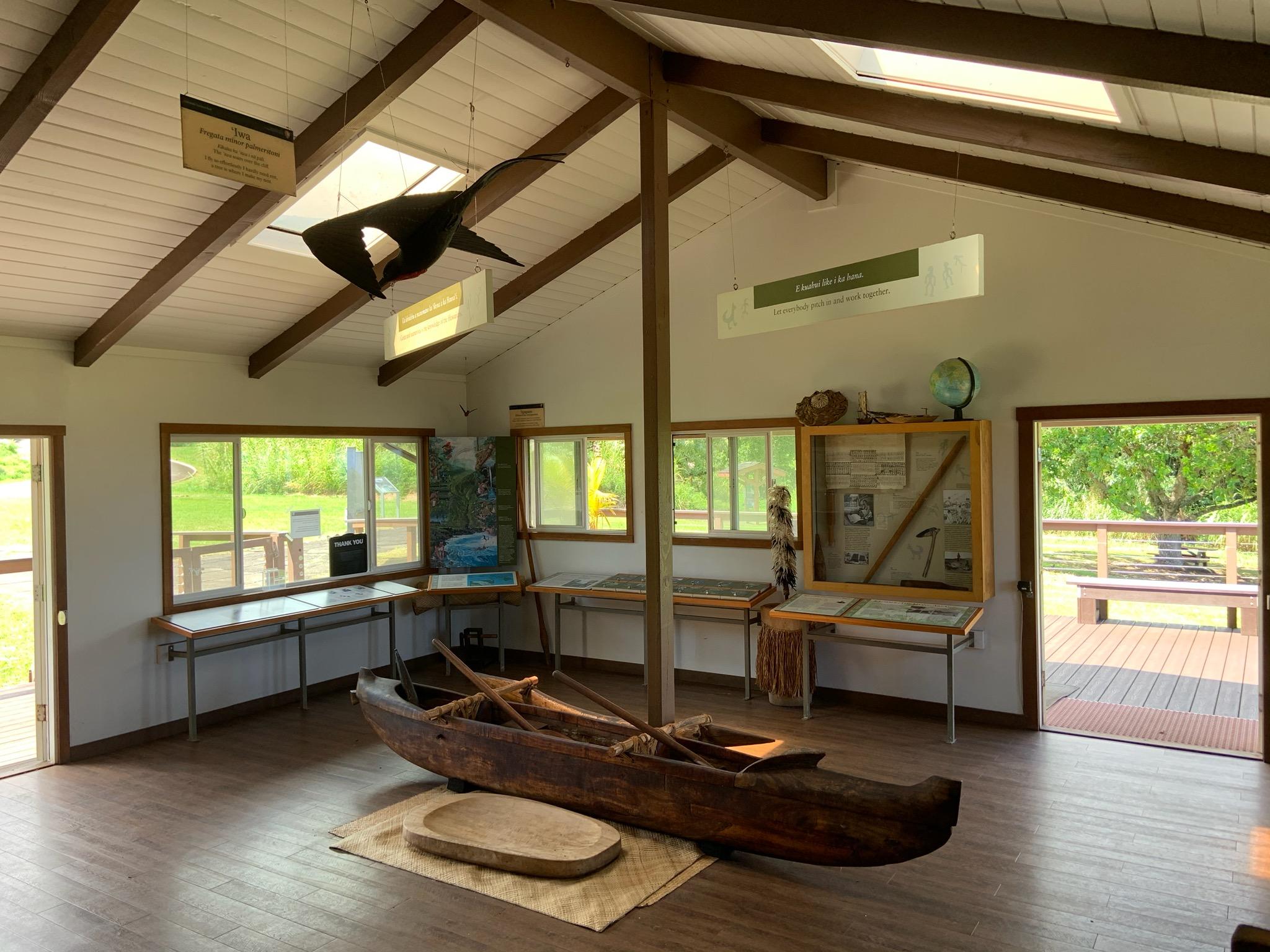 A traditional canoe rests in the center of a sunny exhibit hall.