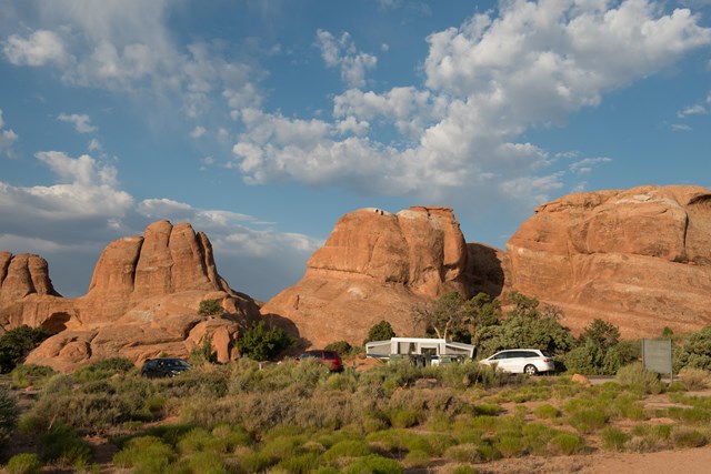 Tall stone formations with cars and trailers beneath them