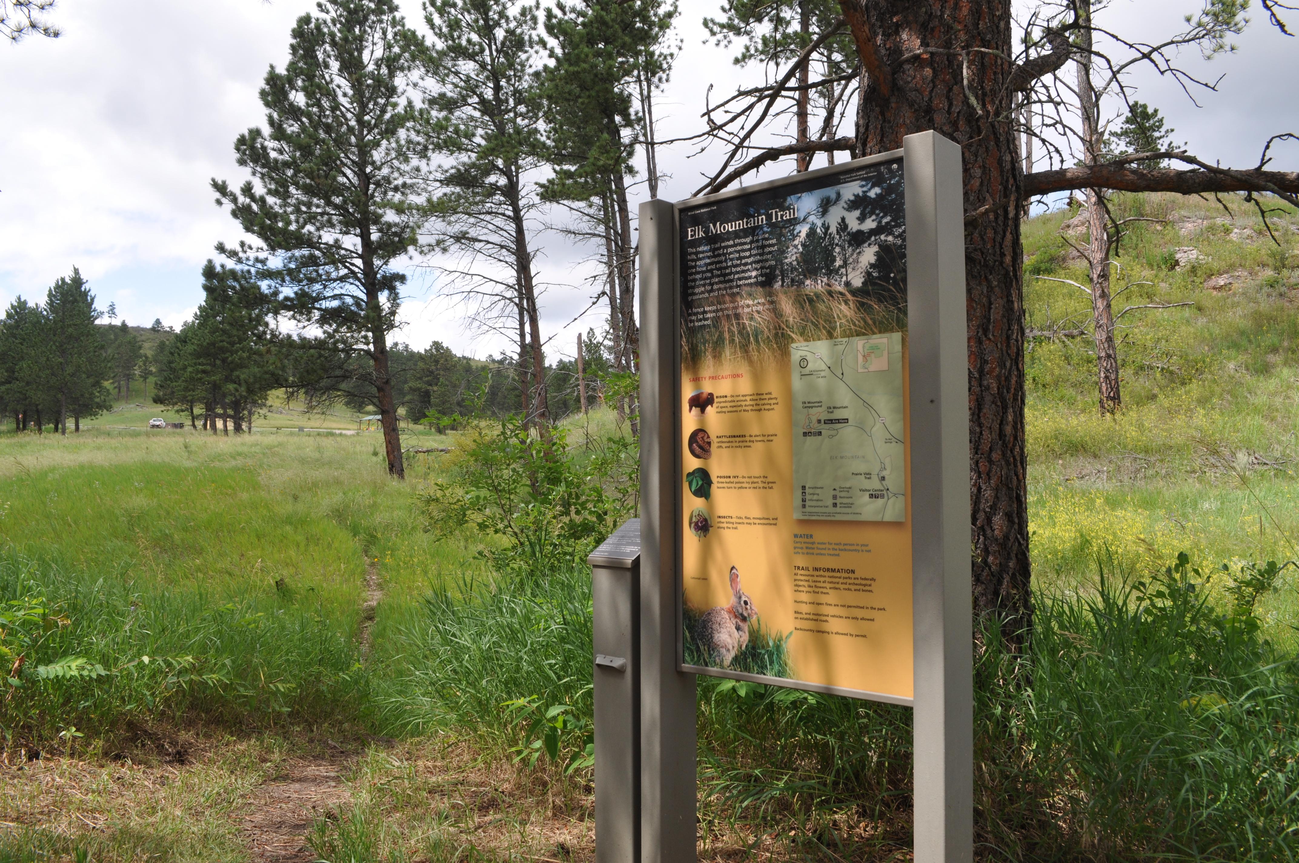 The Elk Mountain Campground Nature Trail sign stands in front of the trail.