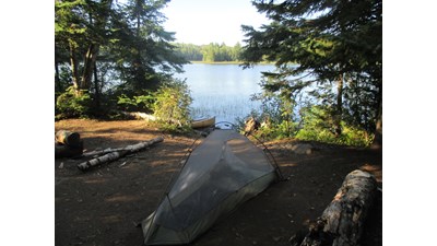 Tent on the shores of Chickenbone Lake with trees along the shoreline.