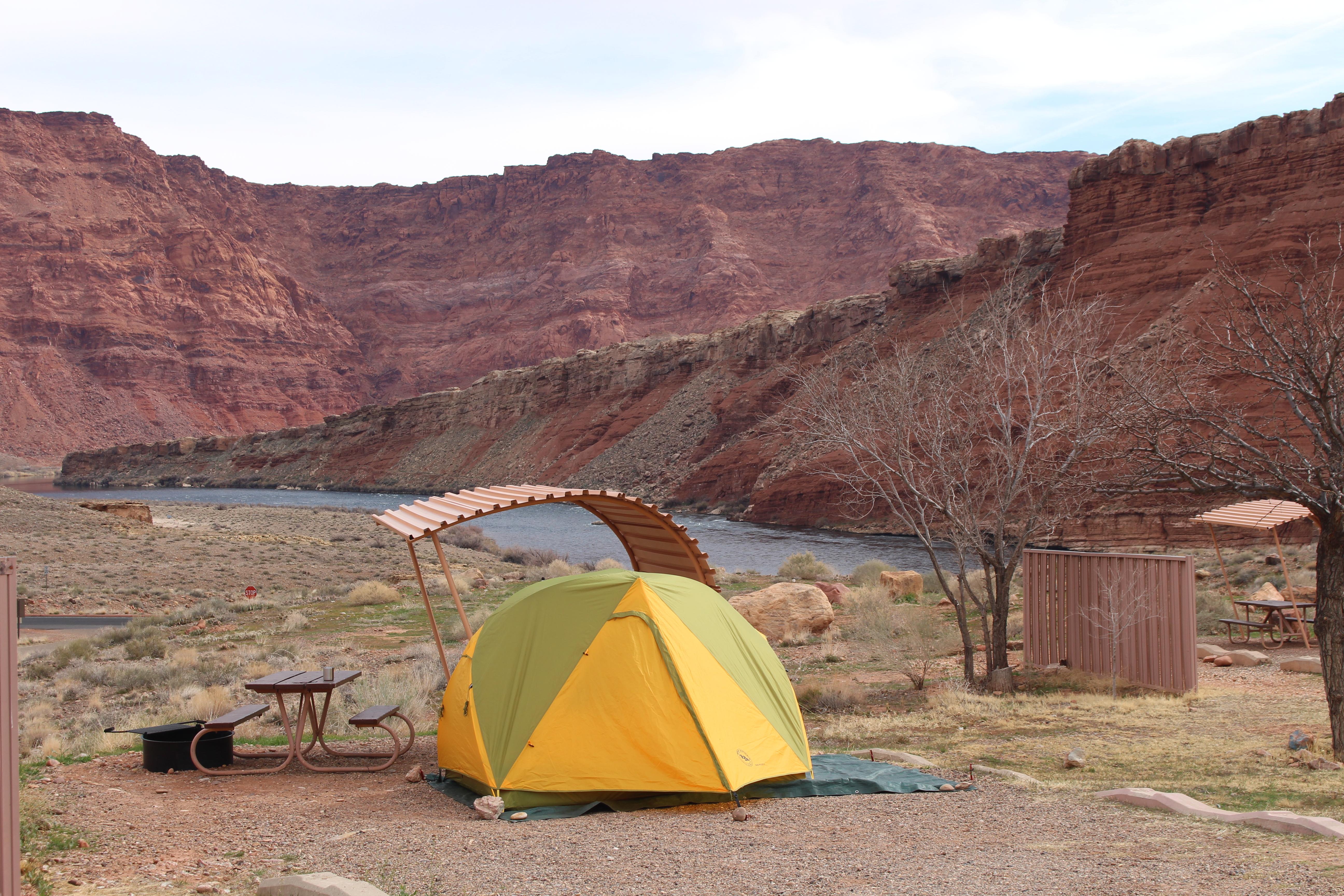 Dome tent and campsite overlooking river and sandstone cliffs