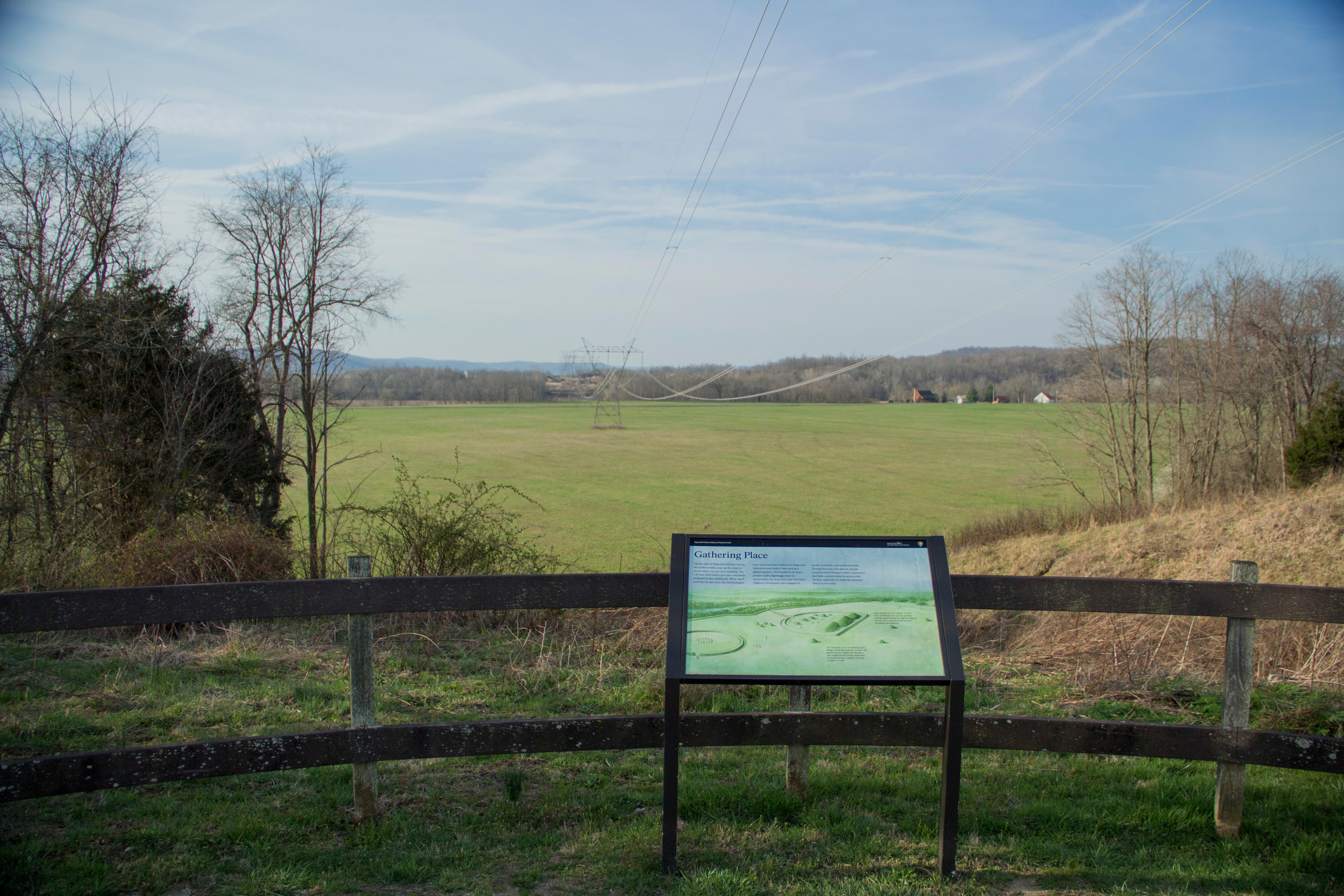 An overlook area showing a green grassy field with a panel showing artwork and text