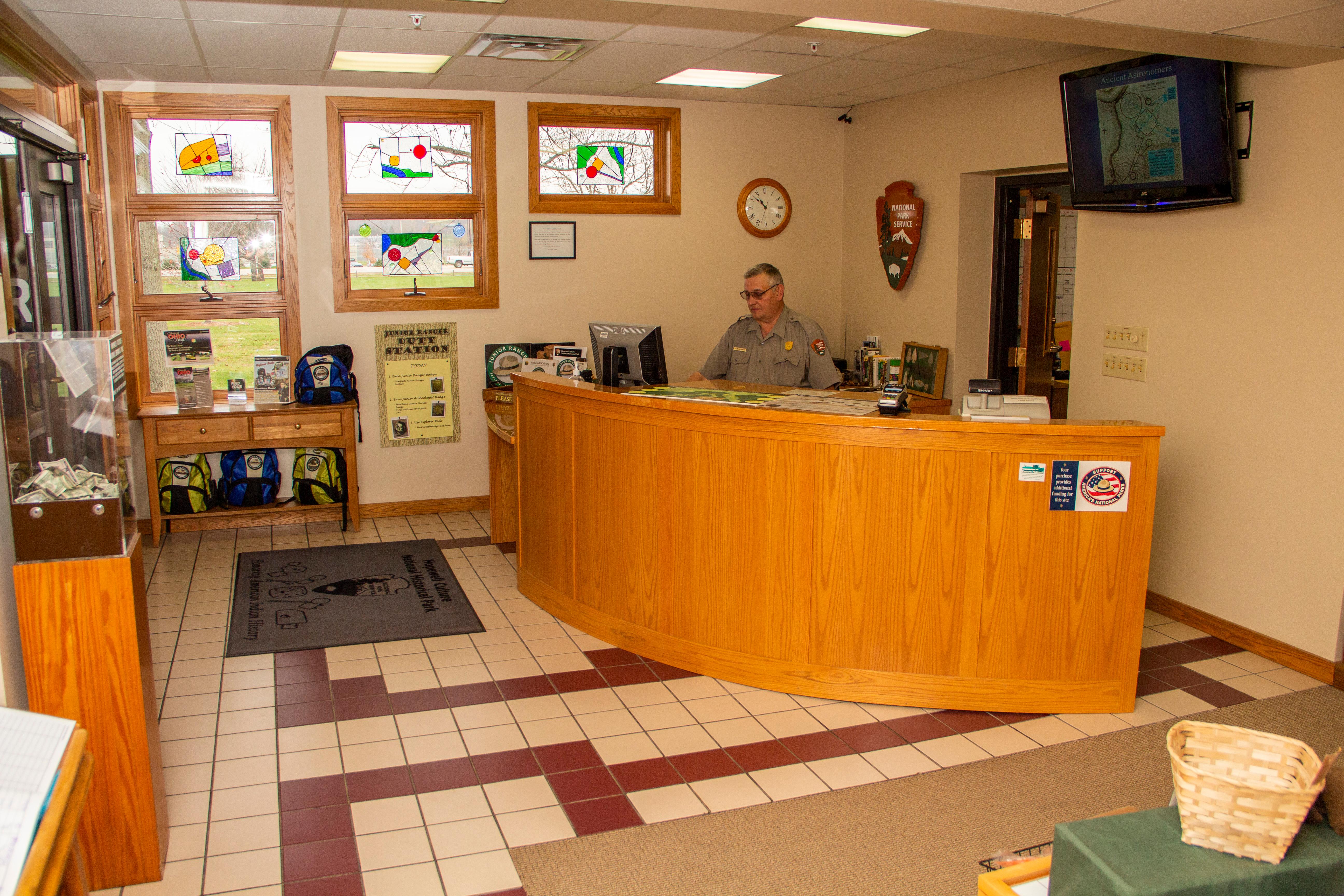 A tan-orange curved information desk with a man sitting behind the counter